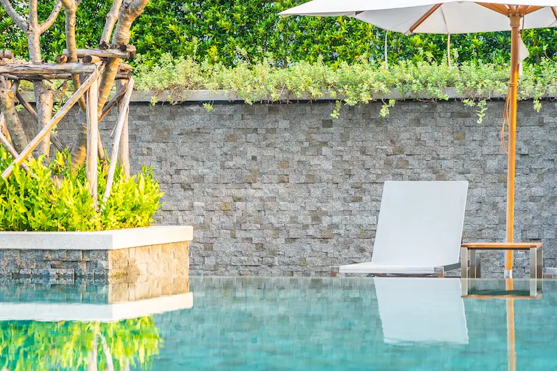 Outdoor pool area with a stone wall, showcasing cost-effective masonry design for exterior projects.